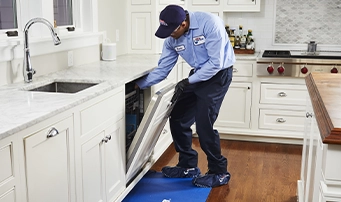 A Roto-Rooter technician performs a final inspection after a dishwasher installation in Dallas