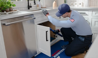 A Roto-Rooter technician services a dishwasher drain line in Dallas