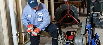 Roto-Rooter technician performing drain cleaning in a Dallas home
