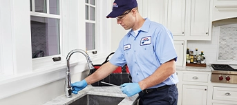 Roto-Rooter technician performing faucet repair in Dallas