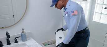 A Roto-Rooter technician in a residential home providing toilet repair in Dallas.