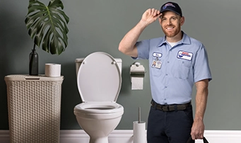 A Roto-Rooter technician standing in front of a functioning toilet after providing toilet repair in Dallas.
