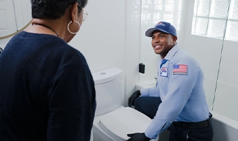 A Roto-Rooter technician speaking to a customer who was in need of toilet repair in Dallas.