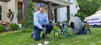 Roto-Rooter technician in front of a house using a machine to access underground sewer lines in Dallas