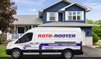 Roto-Rooter van parked in the driveway of a blue house