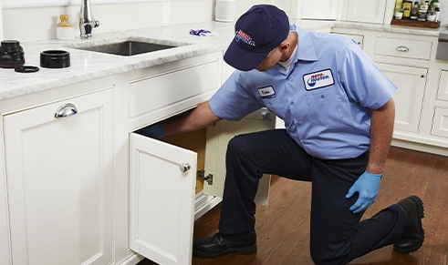 Plumber repairing dishwasher examining pipes underneath sink