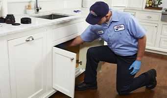 Plumber repairing dishwasher examining pipes underneath sink