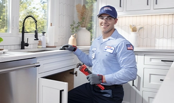 Technician going underneath sink in the process of fixing faucet