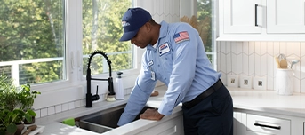 Plumber reaching into clogged garbage disposal