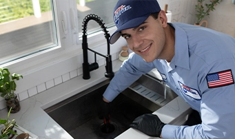 Technician smiling while in the process of repairing garbage disposal