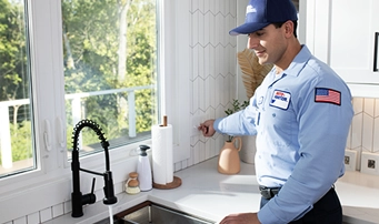 Technician smiling while in the process of repairing garbage disposal