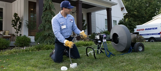 Roto-Rooter technician in front yard repairing sewer