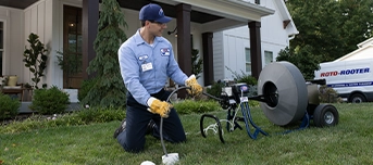 Roto-Rooter technician in front yard repairing sewer