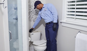 Smiling technician in process of repairing a toilet