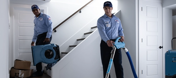 Two Roto-Rooter technicians clean up water in flooded basement