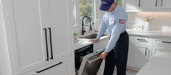 A Roto-Rooter technician inspecting an old dishwasher during a dishwasher repair in Minneapolis