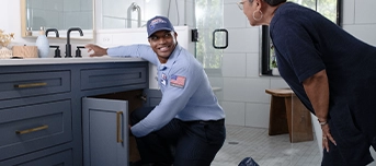 A technician is inspecting the sink and talking to a customer about faucet repair in Minneapolis.