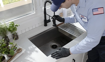 A Roto-Rooter technician examining the sink drain while doing a faucet repair in Minneapolis.
