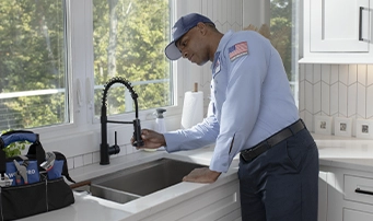 A Roto-Rooter technician inspecting spray nozzle while doing a faucet repair in Minneapolis.