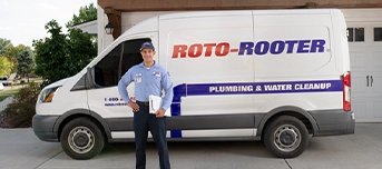 A Roto-Rooter technician standing in front of a work van after arriving at a residential home for a toilet repair in Minneapolis.