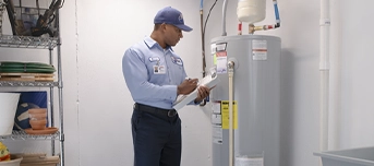 A Roto-Rooter technician is doing an inspection for a water heater repair in Minneapolis and holding a clipboard.