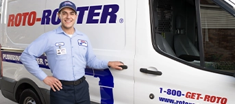 Roto-Rooter emergency plumber in Portland stands outside a Roto-Rooter van with a hand on the door handle