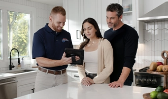 A Roto-Rooter emergency plumber in Portland talks to homeowners in their kitchen