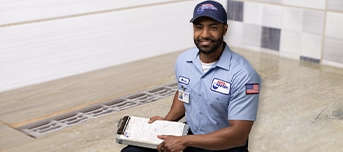 Roto-Rooter technician holding a clipboard with a bathroom drain in the background