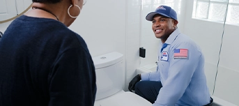 Roto-Rooter technician speaks to female homeowner while doing a toilet repair in Portland