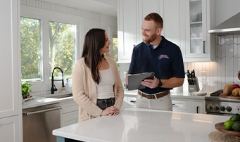 Roto-Rooter rep with clipboard speaks with female homeowner about toilet repair in Portland