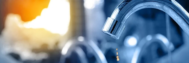 Bathroom water faucet dripping water during a sunrise