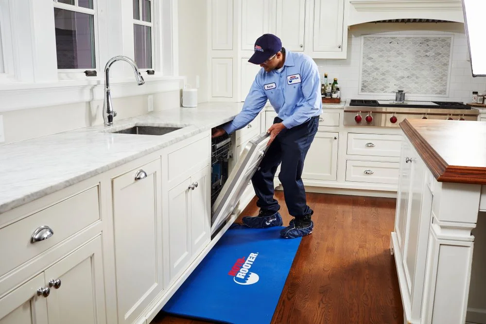 Plumber reaching into dishwasher to complete dishwasher installation in customer's home