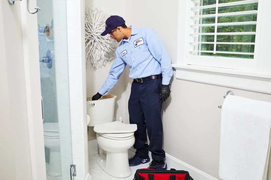 Plumber with hand in toilet tank