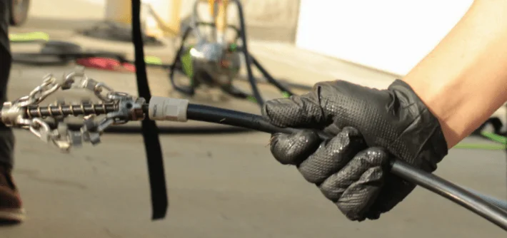 Plumber preparing for descaling service holding flexible cable with chain knocker attached