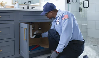 Roto-Rooter plumber repairing leak in kitchen sink drain