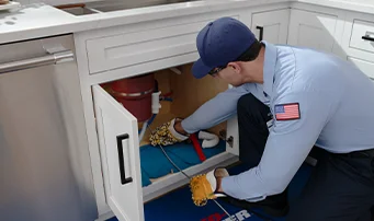 Plumber unclogging garbage disposal